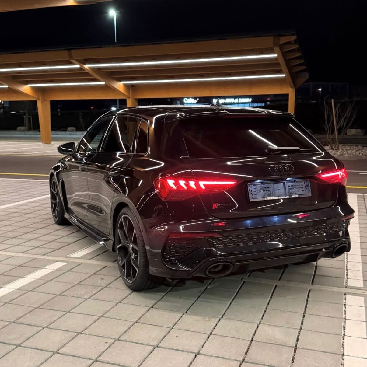 Audi RS3 Sportback noire, de nuit, vue de trois quarts arrière