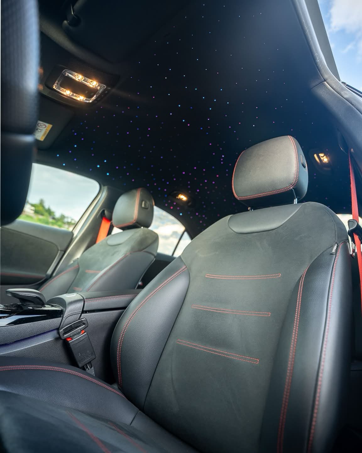 Intérieur d'une voiture du club : ciel étoilé au pavillon et sièges AMG surpiqués de rouge