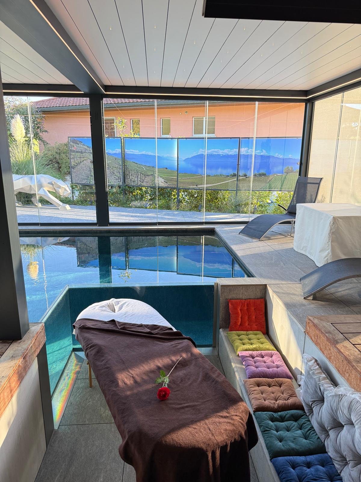 Une rose rouge posée sur la table de massage de Secret Paradise, devant la piscine et la vue sur le lac